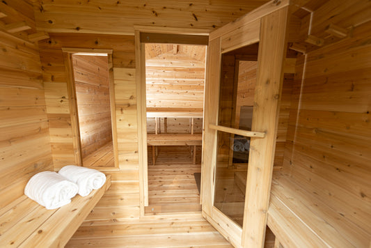 Inside a cedar cabin sauna with rolled white towels on the bench